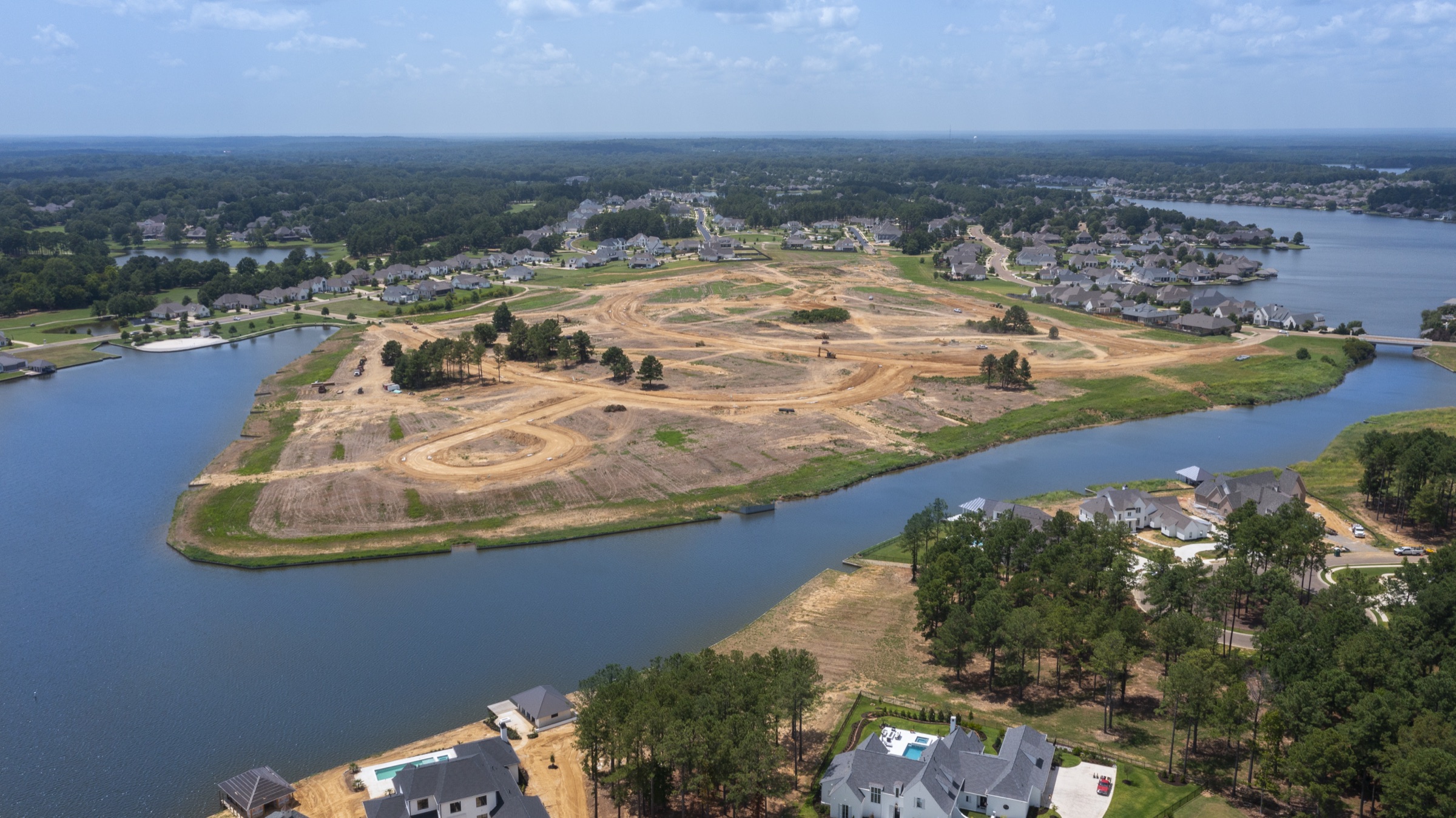 Aerial view of the Reunion development in Madison, Mississippi, showing lakeside lots under preparation among established homes.